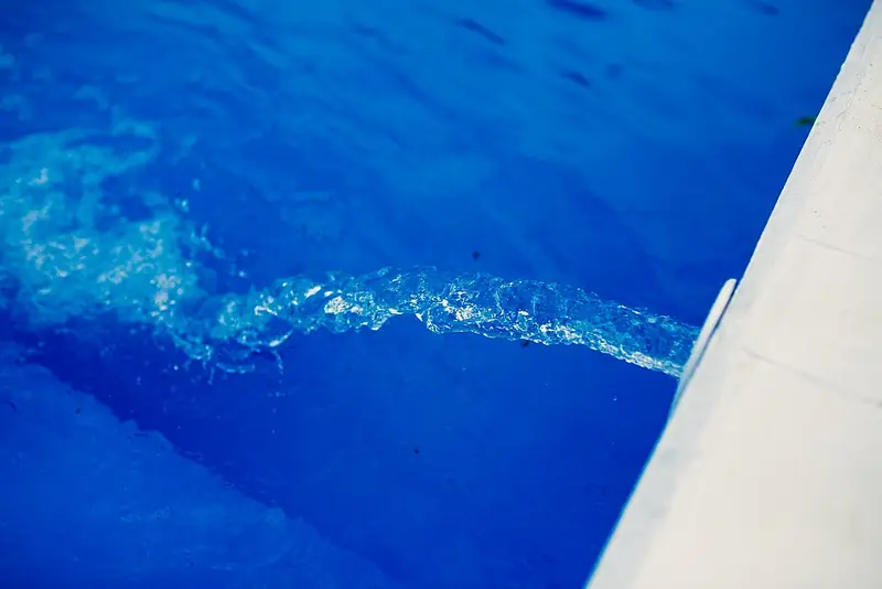 Water flowing into a clear blue swimming pool
